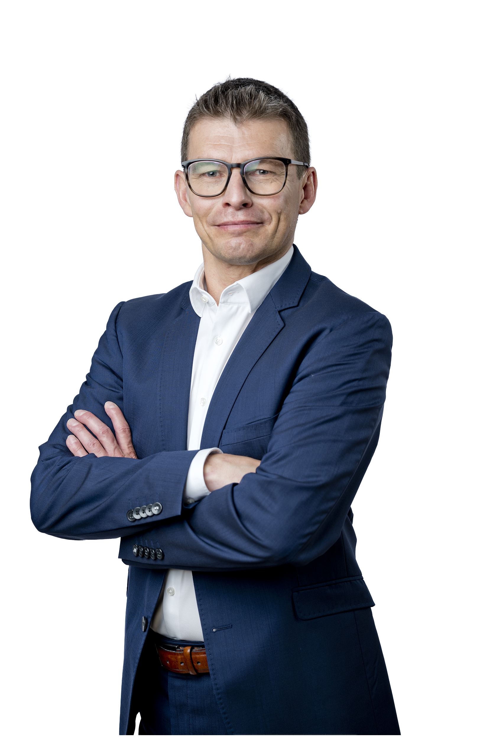 Porträt eines Mannes mit Brille im dunkelblauen Anzug und weißem Hemd, der mit verschränkten Armen vor hellem Hintergrund steht.