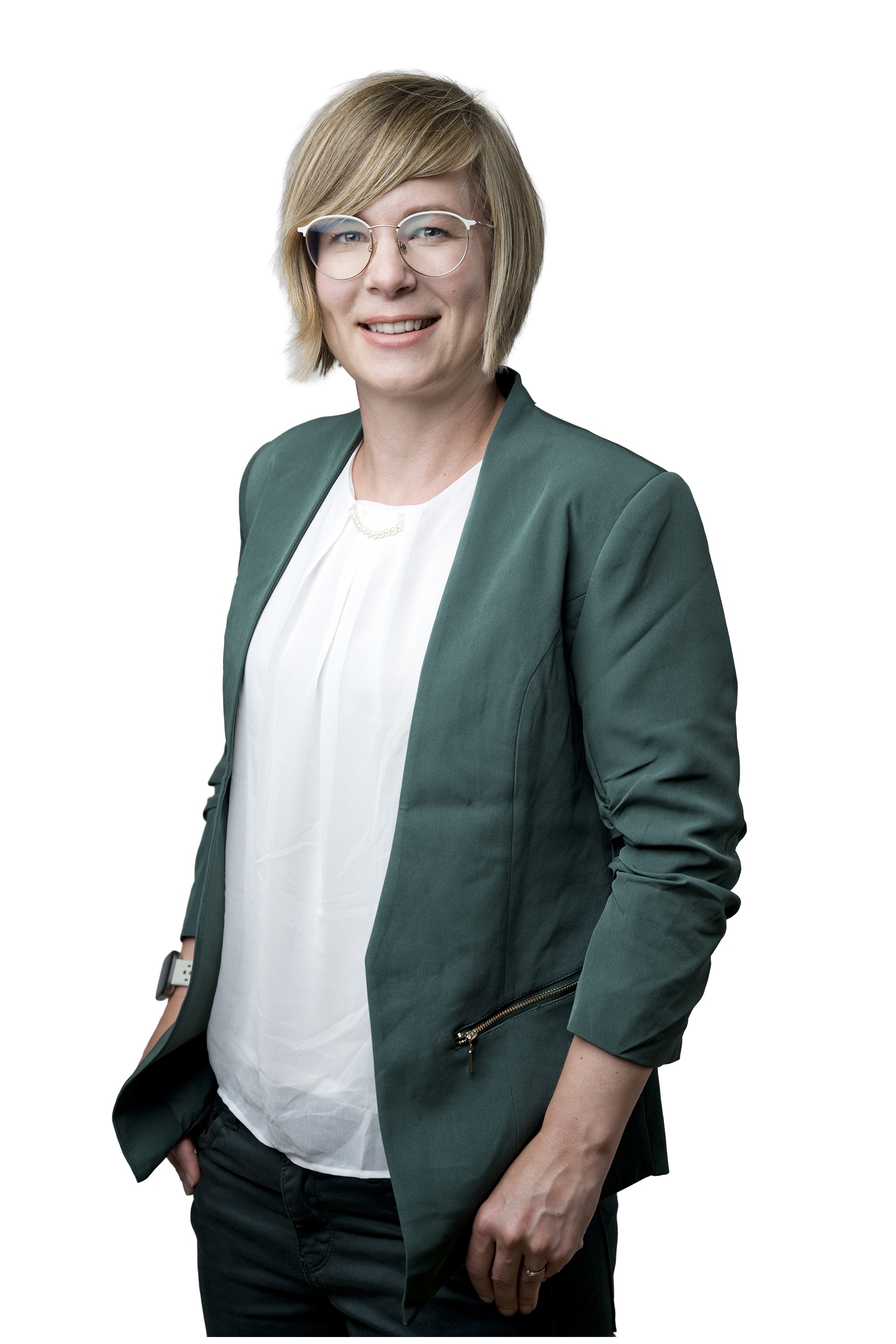 Porträt einer lächelnden Frau mit Brille, kurzem blondem Haar, weißer Bluse und dunkelgrünem Blazer vor grauem Hintergrund.