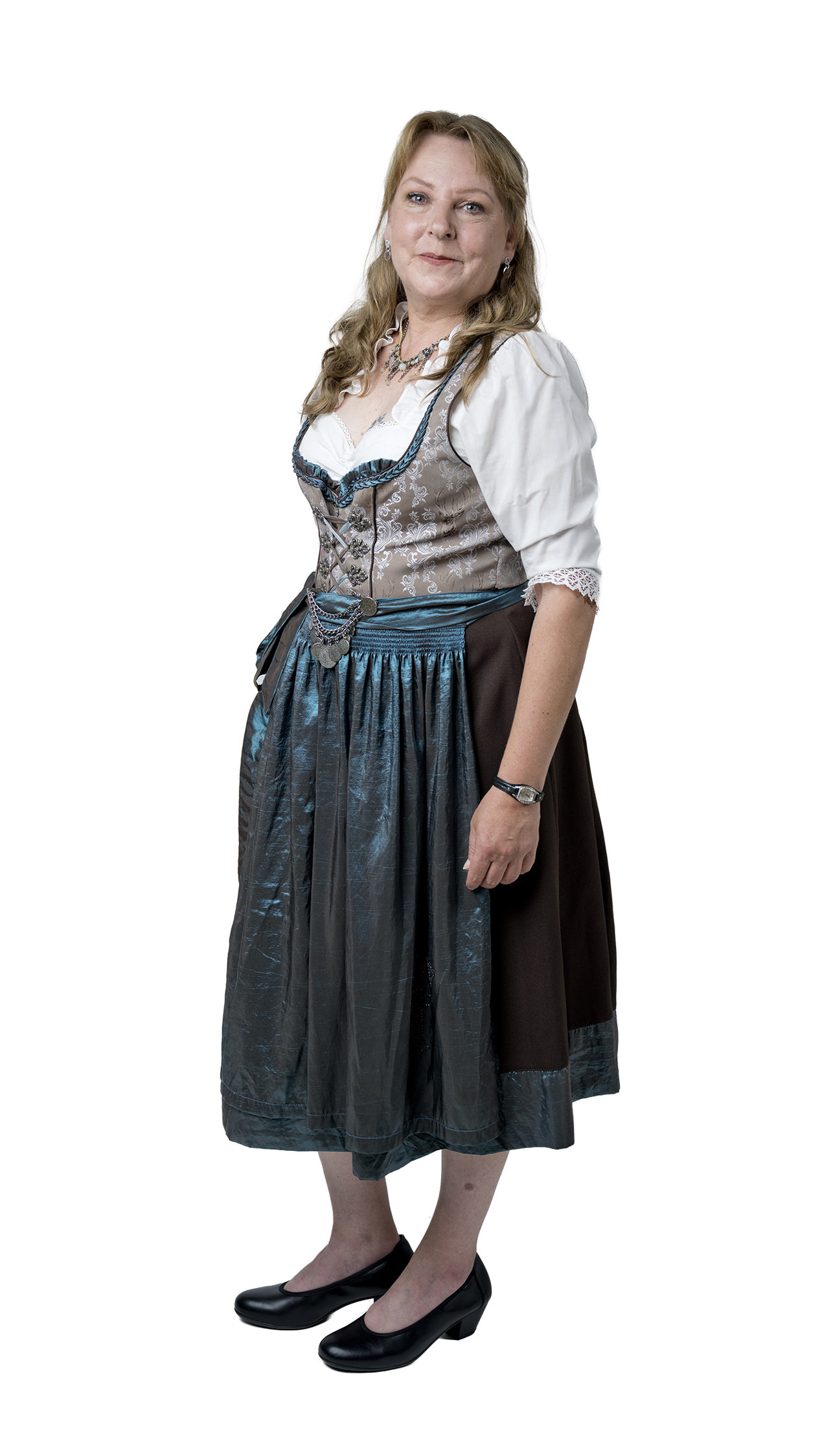 Eine lächelnde Frau steht in traditioneller bayerischer Tracht mit weißer Bluse, verzierter Weste, blauem Dirndlrock und schwarzen Pumps vor hellem Hintergrund.