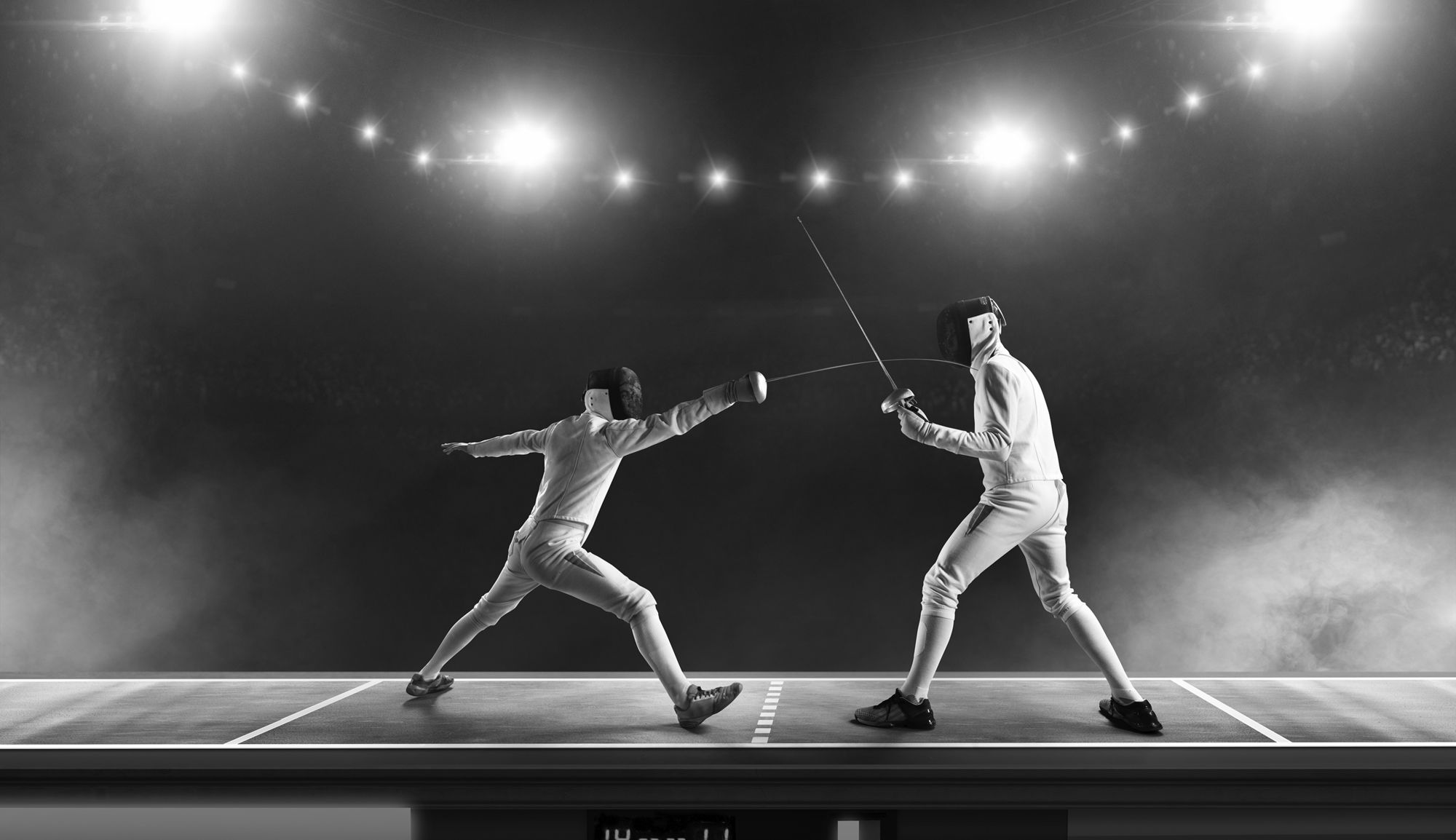 Two fencers in protective gear face each other with raised épées on an illuminated fencing piste.
