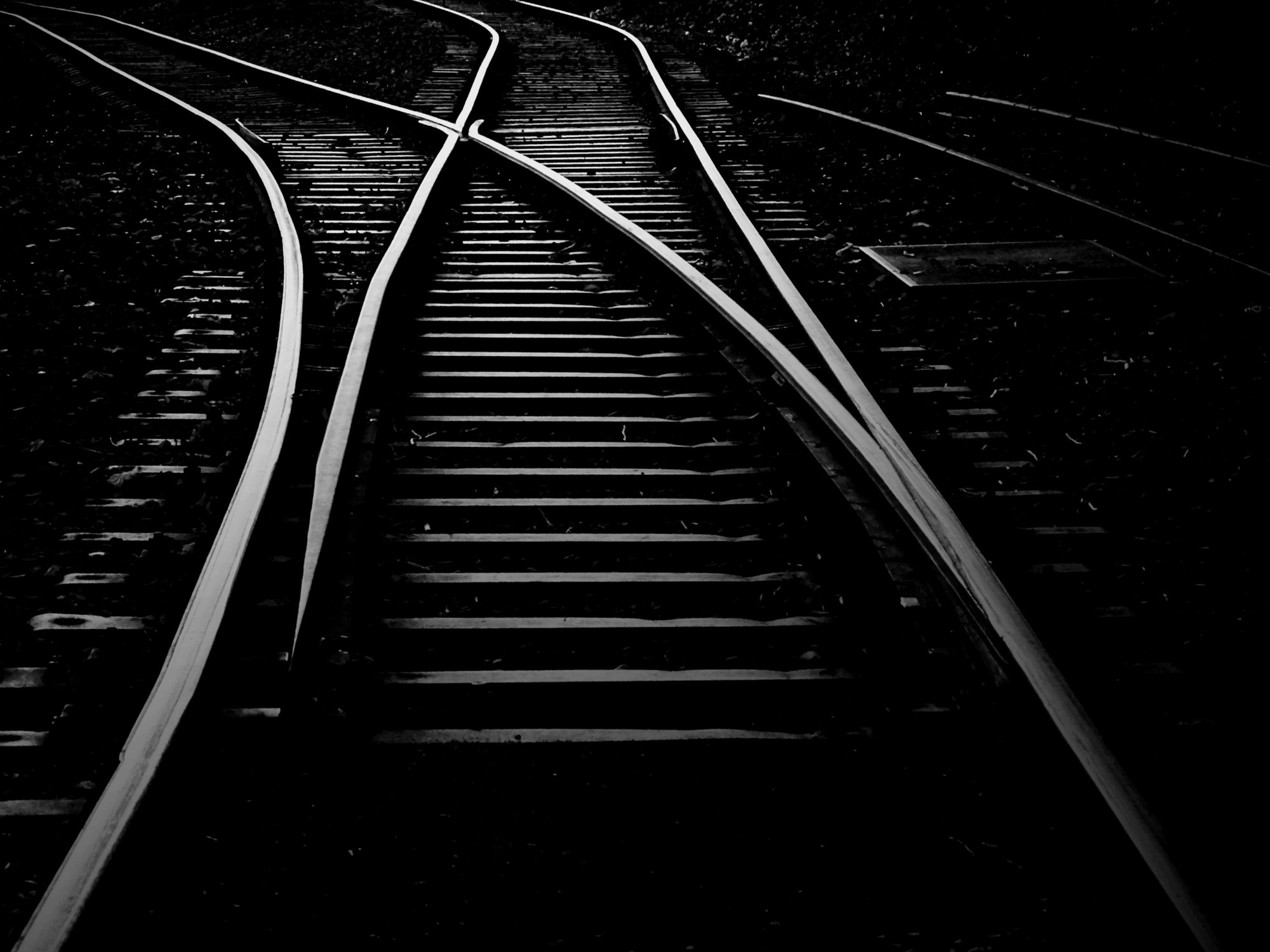 Black-and-white photograph of several merging railway tracks with switches and wooden sleepers.
