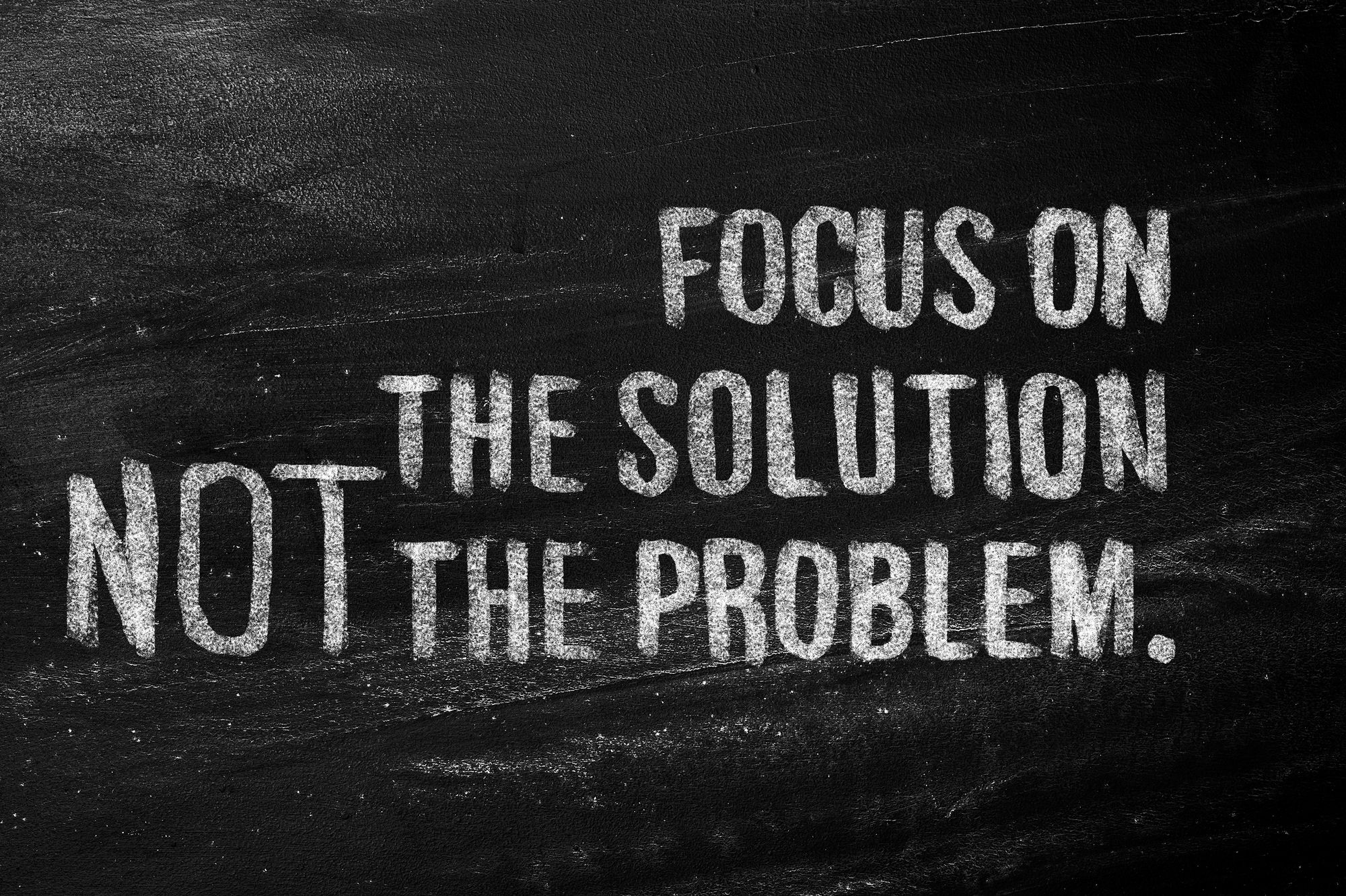 Blackboard with white lettering: “FOCUS ON THE SOLUTION NOT THE PROBLEM.”