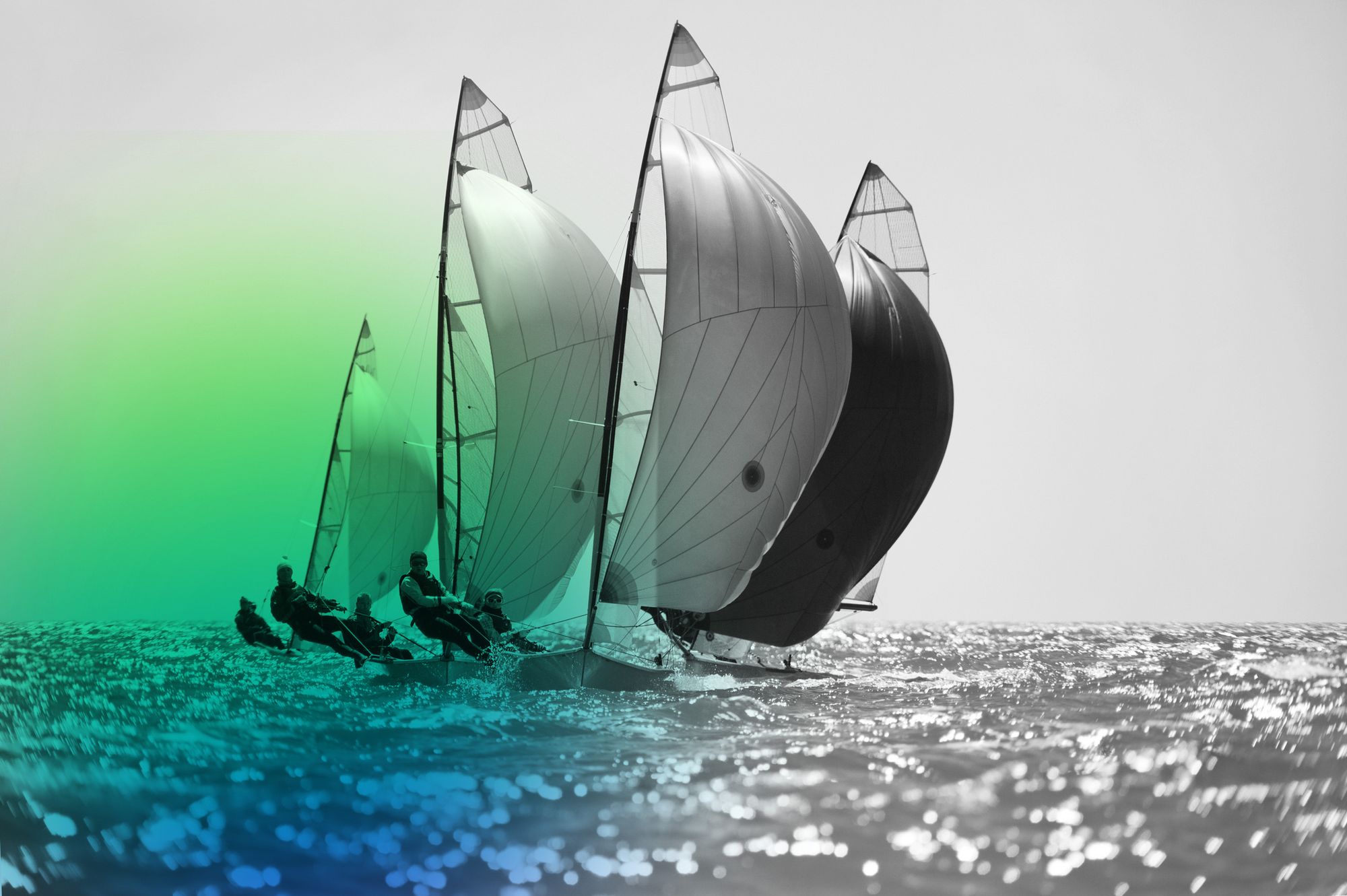 Several sailboats with large, billowing spinnakers and their crews sail across choppy, sparkling water.